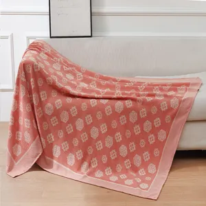 Detail view of the soft pink decorative blanket featuring delicate floral patterns on sofa.