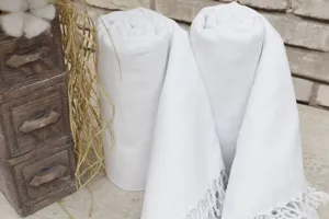 White rolled Turkish beach towel detail with delicate fringe, rustic cotton fabric texture