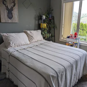 Detailed view of the striped woven cotton blanket with cute tassels in a cozy bedroom setting.