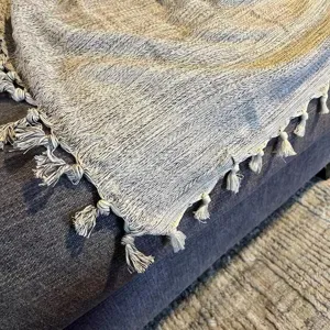 Detailed view of a woven cotton throw blanket featuring textured stripes and elegant fringes.
