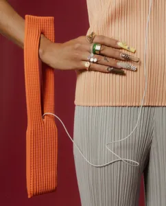 Detailed view of fashionable orange knit phone bag strap with stylish pleated texture and rings.