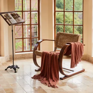 Detailed view of a soft knit throw blanket draped over a wooden chair in a cozy room.