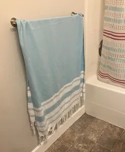 Detailed shot of a light blue Turkish bath towel with white stripes and bottom fringe.