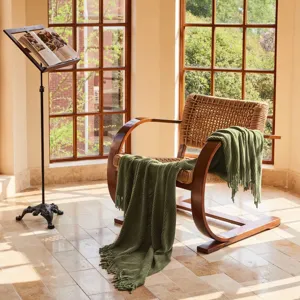 Detailed view of green knitted throw blanket with fringe, cozy texture for sofa or office nap.
