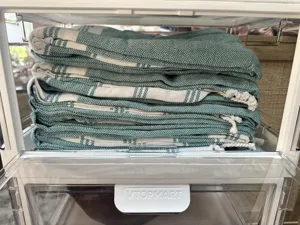 Detailed view of folded green and white striped Turkish beach towel with elegant tassels.
