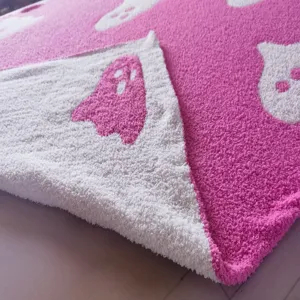 Pink ghost plush blanket detail showing soft knitted jacquard fabric and cozy texture.