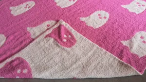 Close-up view of the pink and white ghost pattern knitted jacquard blanket texture details.