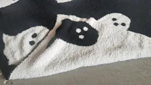Close-up detail of soft black and white ghost pattern fleece throw blanket texture.