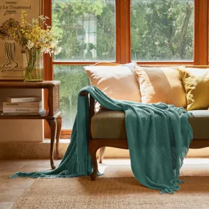 Cozy teal knit throw blanket draped elegantly on a vintage wooden sofa, ideal for home decor.