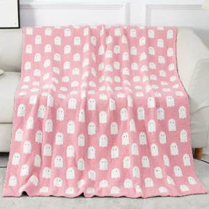 Cozy pink jacquard knit throw blanket featuring cute white ghost patterns for couch decor
