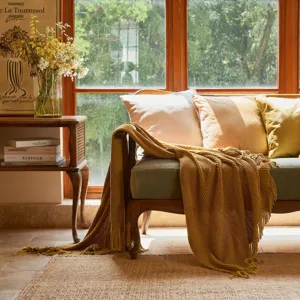 Cozy yellow knitted throw blanket detail, soft textured fringe design for living room sofa.
