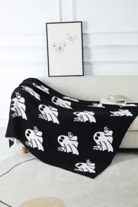 Cozy black and white ghost knitted throw blanket, soft plush fabric for home sofa decor.