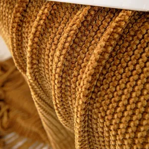 Close-up detail shot of soft textured chenille knitted throw blanket, cozy fabric pattern.