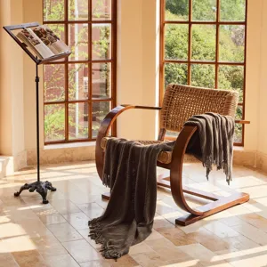 Detailed view of a dark brown knitted throw blanket with tassels draped over a wooden chair.
