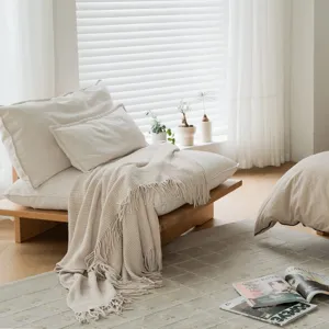 Cozy beige knitted throw blanket with tassels for sofa, bed, and living room decor.