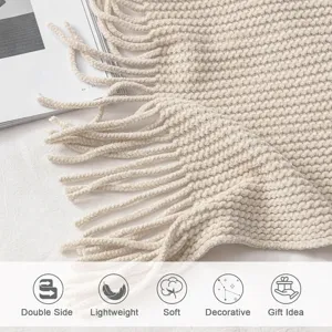 Beige knitted throw blanket detail showcasing soft waffle texture and delicate fringes.