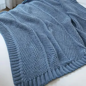 Cozy blue knitted throw blanket with textured diagonal stripe design for sofa and bed.