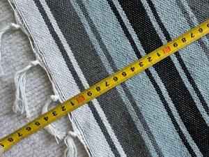 Close-up detail of woven Mexican blanket with multi-color stripes and fringe design.