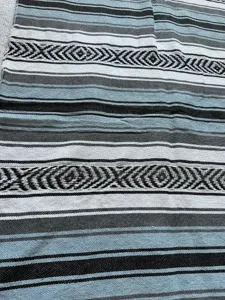 Woven Mexican blanket detail showing classic geometric stripes and soft cotton fabric texture.
