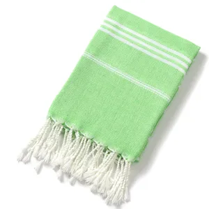 Primo piano dettagliato del telo mare turco verde con strisce e frange bianche.