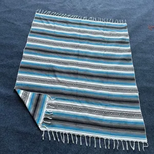 Woven Mexican blanket with geometric stripes and fringe, ideal for beach, picnic or yoga.