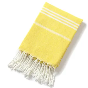 Primo piano di un telo mare turco giallo con strisce bianche e dettagli in frange.