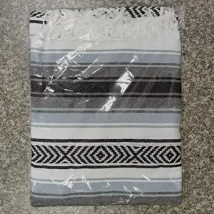 Woven Mexican blanket detail with geometric stripes and fringe, perfect as a beach mat or yoga rug.
