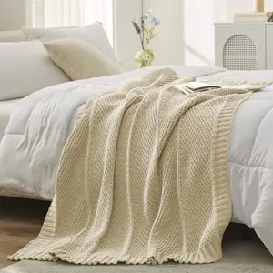 Close-up detail of cozy beige knitted throw blanket texture, soft bedroom bedding scene setup.