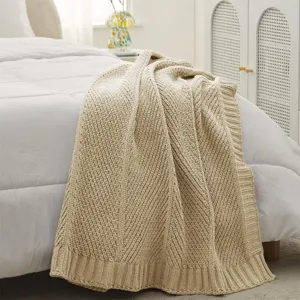 Close-up detail of soft beige diagonal stripe knitted throw blanket for cozy home decor.