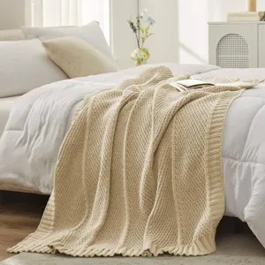 Cozy beige knitted throw blanket detail shot showcasing soft texture and diagonal pattern.