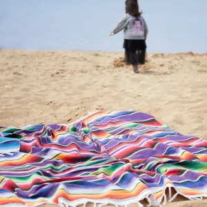 Colorful striped woven cotton blanket with fringe for beach camping and outdoor picnic use.