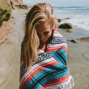 Detailed outdoor beach lifestyle shot highlighting the vibrant woven stripes and fringe.