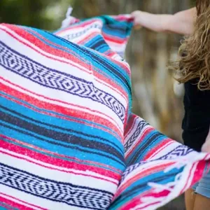 Detailed view of woven Mexican blanket with colorful geometric stripes and fringe tassels.