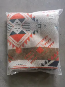 Detailed view of bohemian geometric patterned knitted blanket, neatly folded in a clear package.