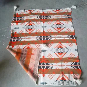 Woven jacquard throw blanket detail showing bohemian geometric pattern and corner tassels texture.