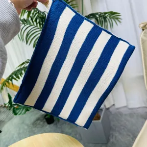 Vista detallada de la bolsa de pañuelos tejida a rayas azules y blancas para el hogar.