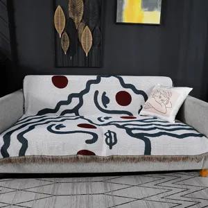 Nordic style knitted sofa towel blanket with abstract face art design and fringe trim.