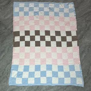 Close-up of soft knitted jacquard checkerboard blanket with pastel blue, pink and brown blocks.
