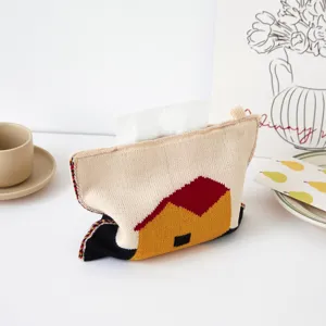 Primer plano detallado de una bonita funda de pañuelos tejida con un acogedor diseño de casa.