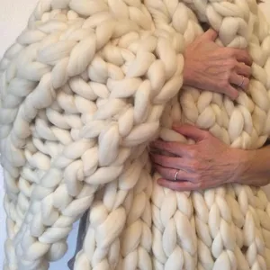 Close-up detail of handmade chunky knit wool blanket showing ultra-thick texture and cozy feel.