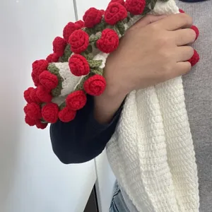 Handmade crochet blanket detail, showing white fabric and red 3d rose flower decoration close up.