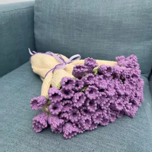 Detail shot of handmade crochet rose flower bouquet blanket showcased on soft blue fabric.