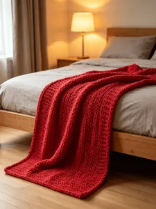 Chunky red knit throw blanket for sofa and bed, handmade thick yarn cozy texture bedroom detail.