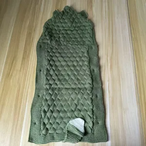 Detailed view of the green knitted baby sleeping bag, featuring a cozy textured crocodile pattern.