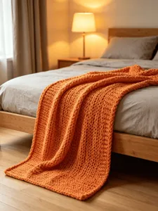 Detailed view of cozy orange chunky knit blanket, soft chenille throw for sofa and bed decor.