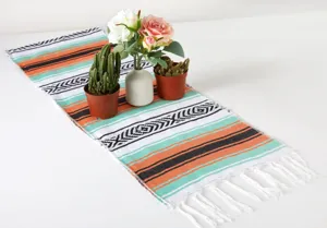 Primo piano dettagliato di un runner da tavola messicano colorato con frange decorative.