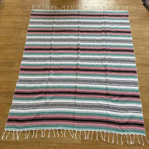 Woven Mexican blanket with diamond jacquard stripes and fringes for beach and outdoor picnic use.