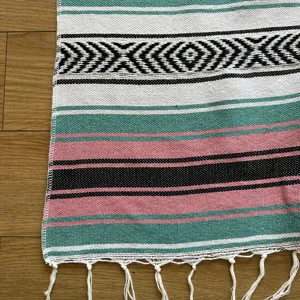 Detailed close-up view of woven geometric striped blanket featuring decorative fringe tassels.