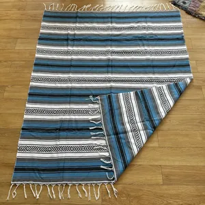 Mexican woven blanket with geometric striped pattern and fringe, ideal for beach and outdoor picnic.