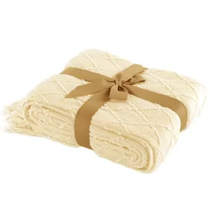 Detailed view of a cozy beige knitted blanket featuring elegant tassels and a neat brown ribbon tie.